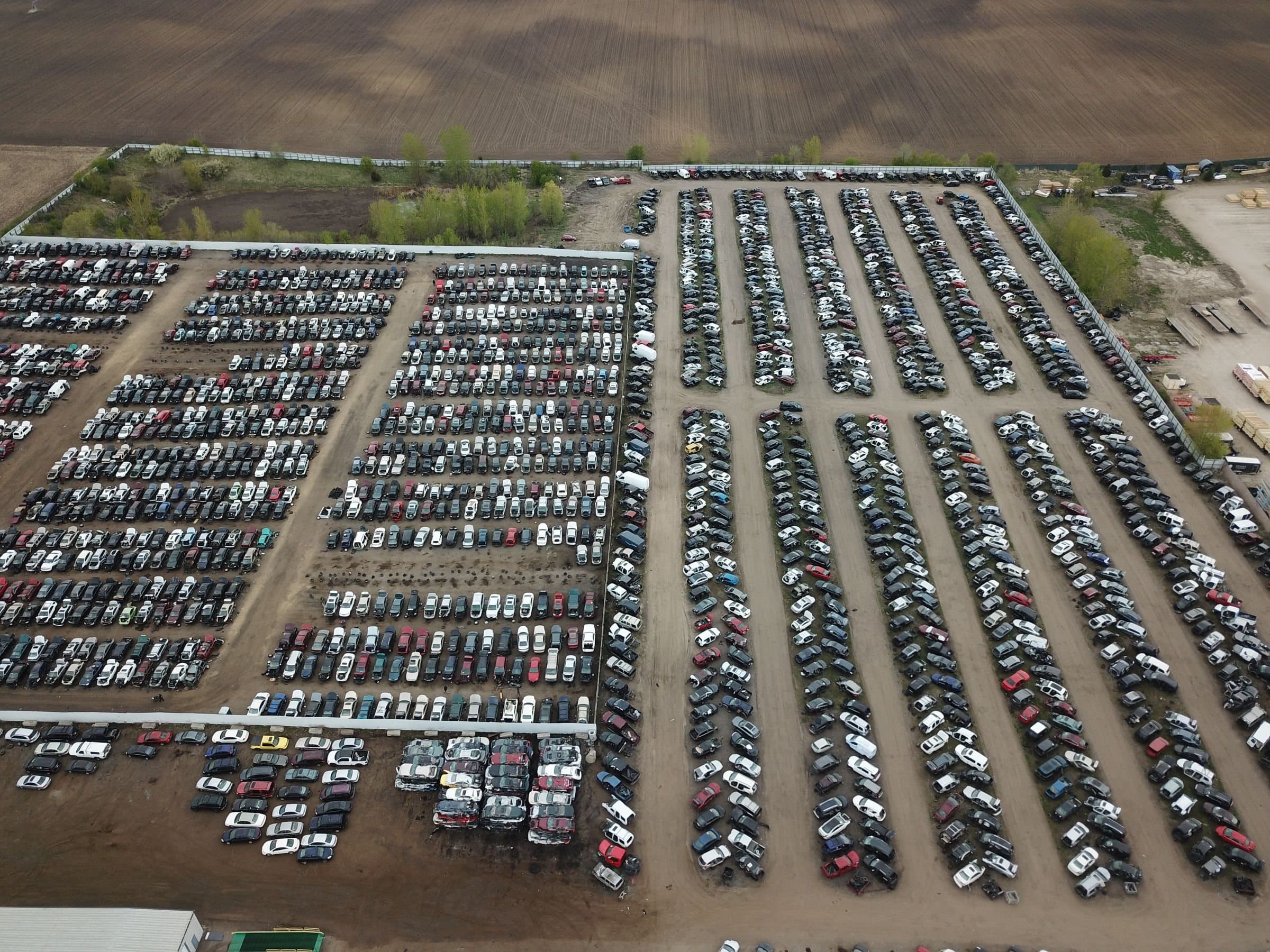 Aerial view of a vehicle auction yard with long rows of cars