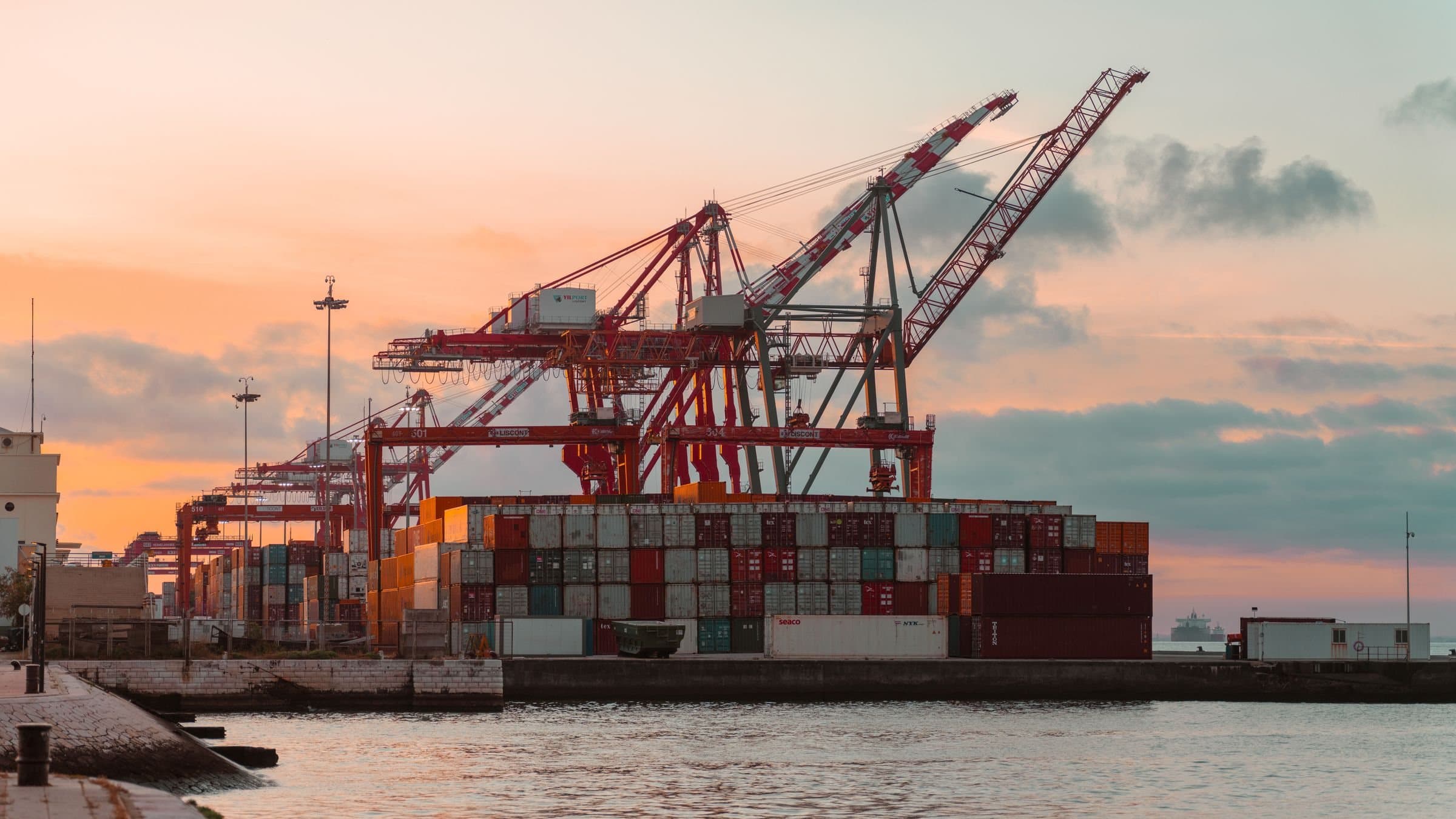 Port cranes and a container ship at sunset