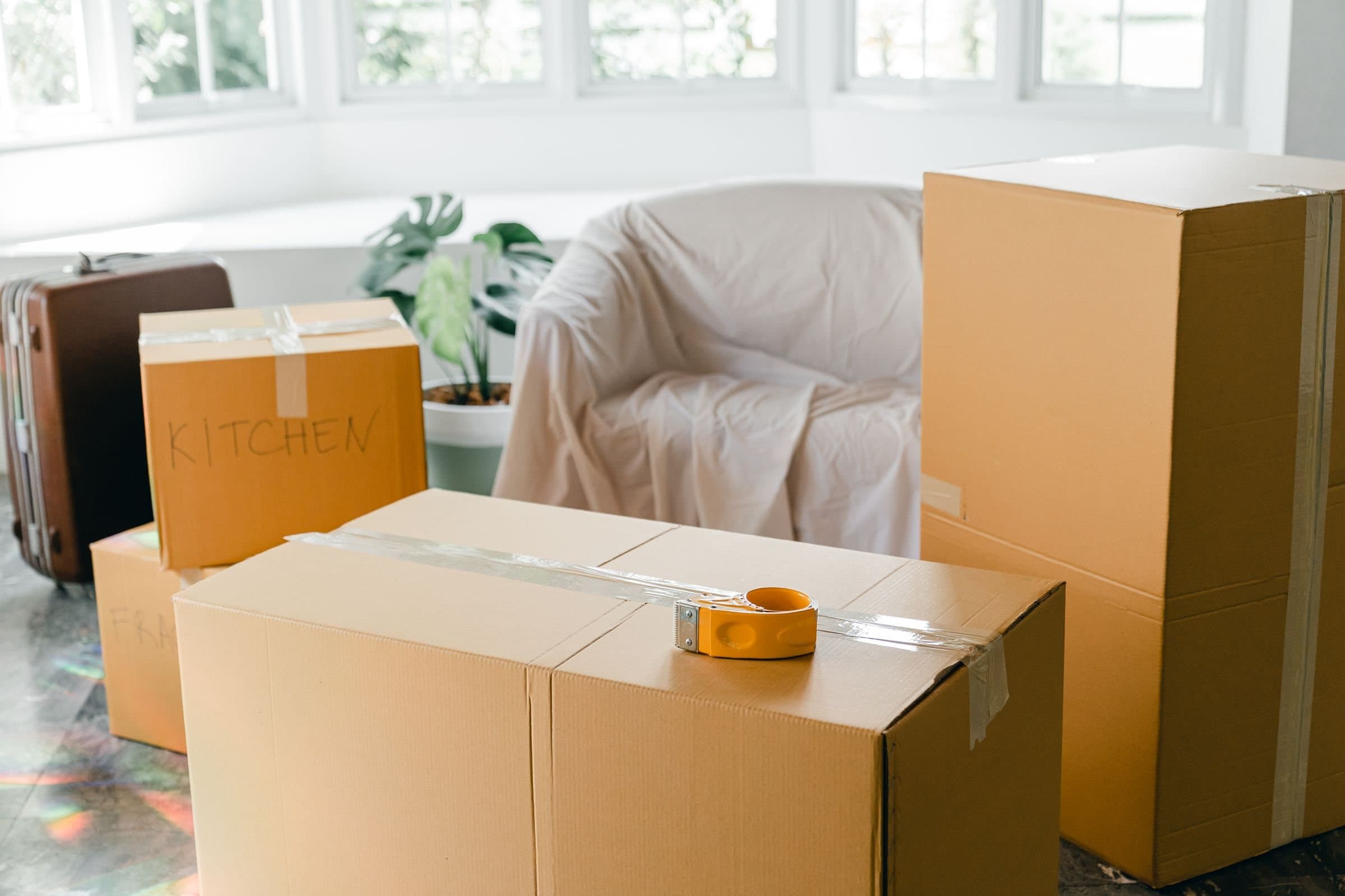 Packed moving boxes and covered furniture in an empty room